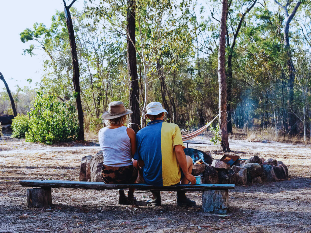 A cozy outdoor event with guests gathered around a bonfire, enjoying a spit roast.