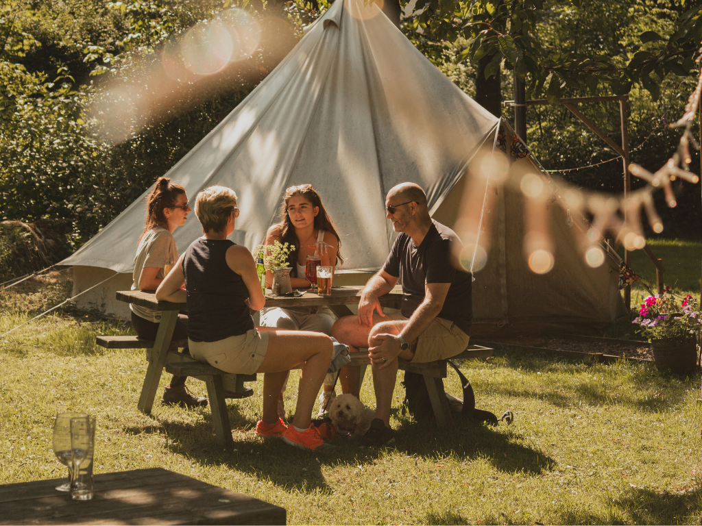 A unique celebration setting featuring luxury glamping tents, fairy lights, and an intimate outdoor dining setup.
