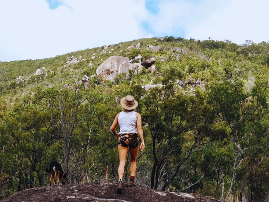 A determined runner sprinting along a rugged trail, surrounded by lush greenery and open skies.